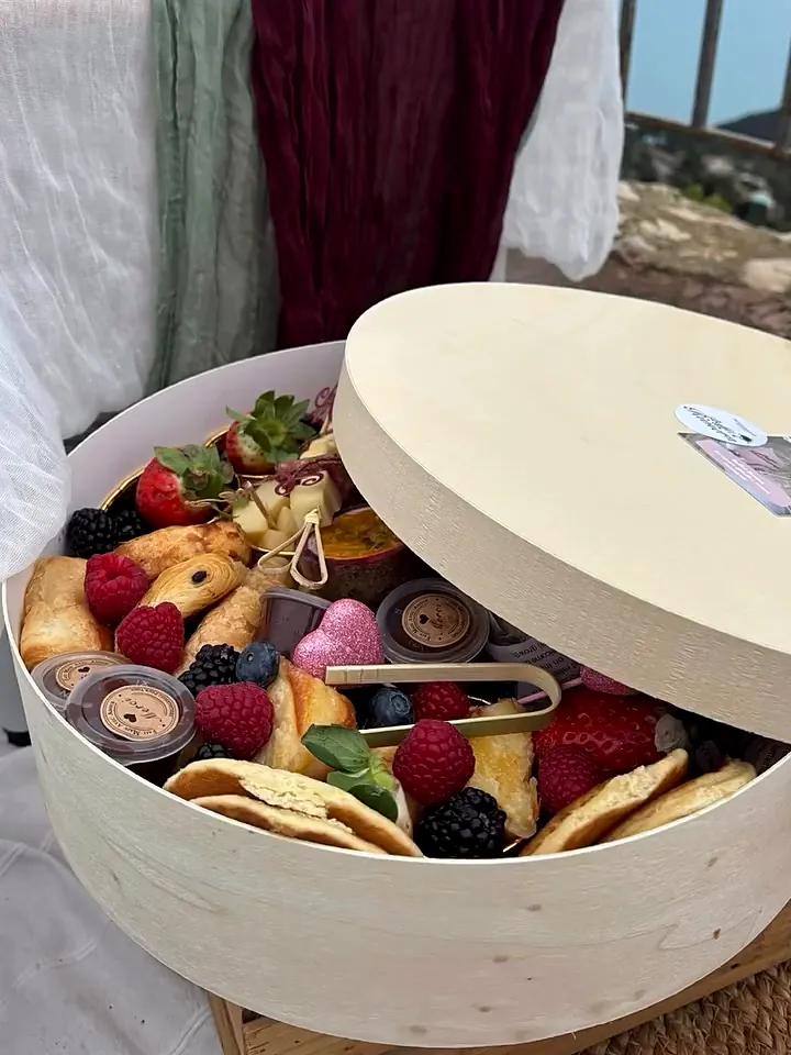 Box brunch ronde ouverte, garnie de fruits, viennoiseries et douceurs