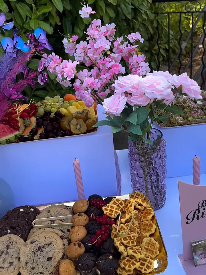 Buffet décoré de fleurs roses et violettes avec cookies, gaufres et coupes de fruits rouges